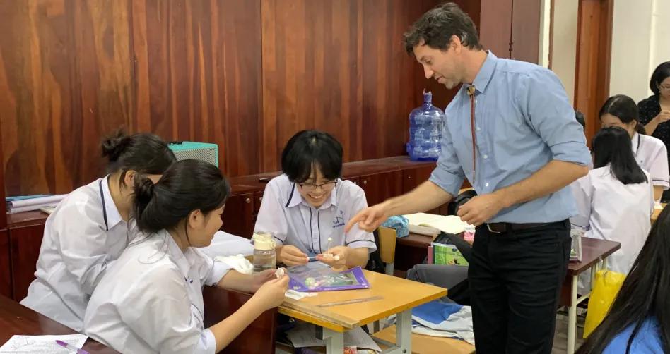 Fulbright Teacher with three students in Vietnam